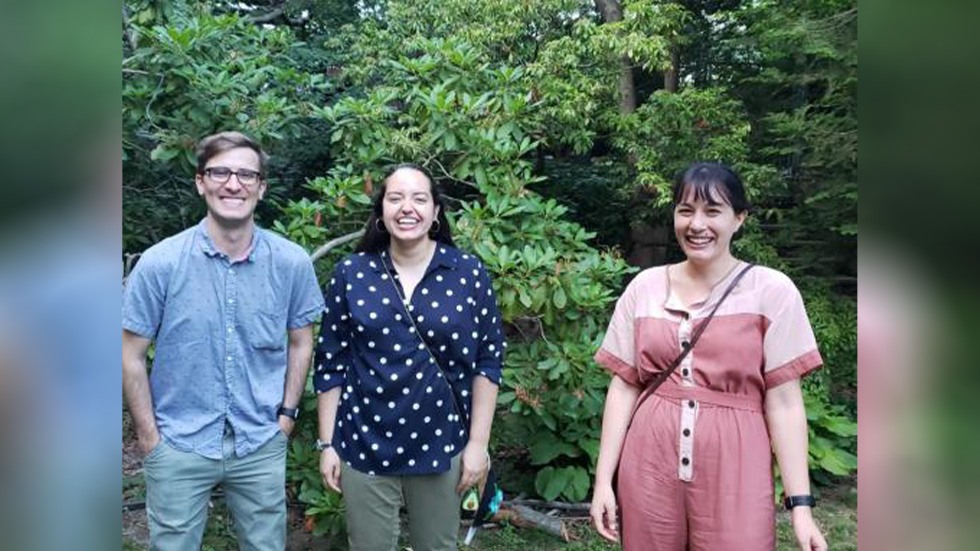 three people posing for a photo outside