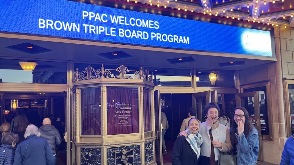 three people in front of a theater marquee